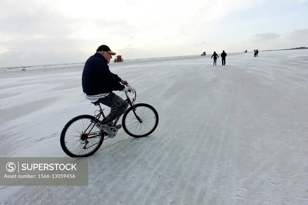SARSOTA, FLORIDA. Retired 80 year old man on bicycle on beach.