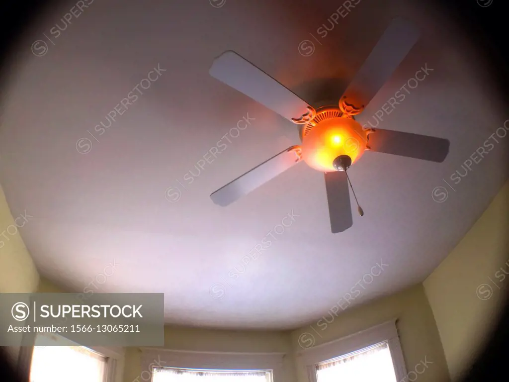A ceiling fan with lights on a round surface in a room with bay windows, Ontario, Canada