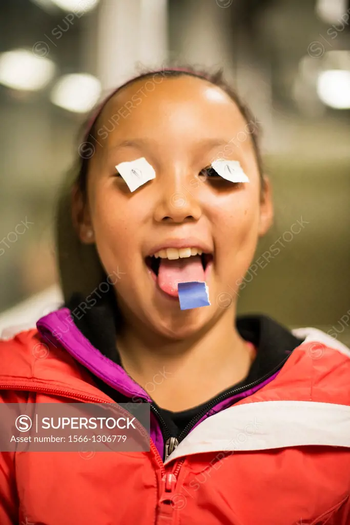 Girl, 10, playing with paper on her eyes.