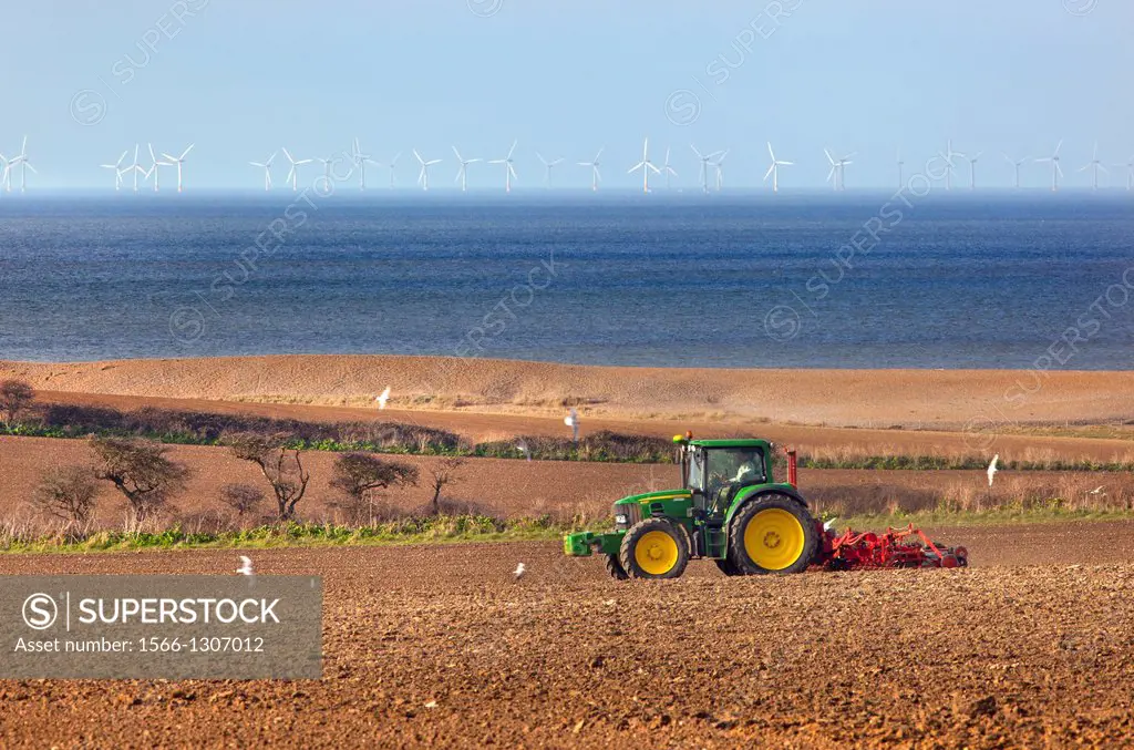 Seed drilling at Cley Norfolk in Spring and off shore windfarm.