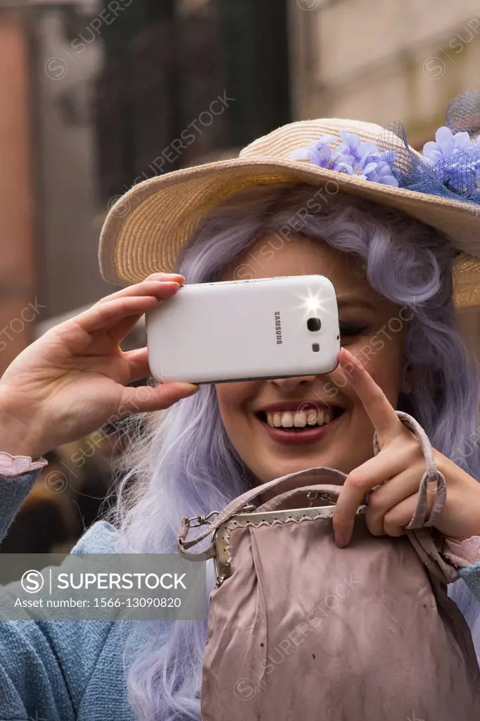 Woman taking a photo with her smartphone during Venice Carnival. Venice. Italy