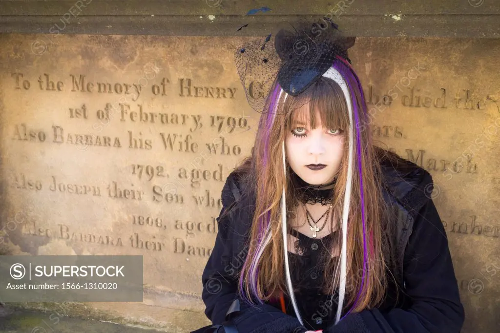 Goth posing for photographers in cemetery at Whitby Goth Weekend, Whitby, North Yorkshire, England, United Kingdom. The biannual event attracts thousa...
