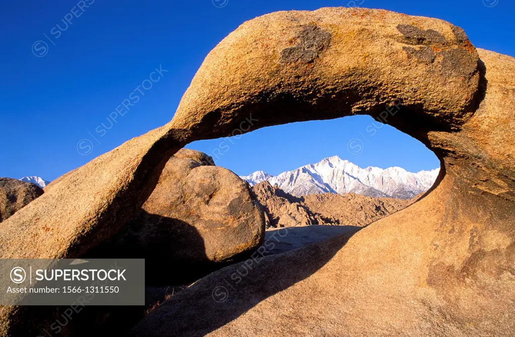 Morning light on Lone Pine Peak in winter through rock arch in the Alabama Hills, Inyo National Forest, Sierra Nevada Mountains, California USA.