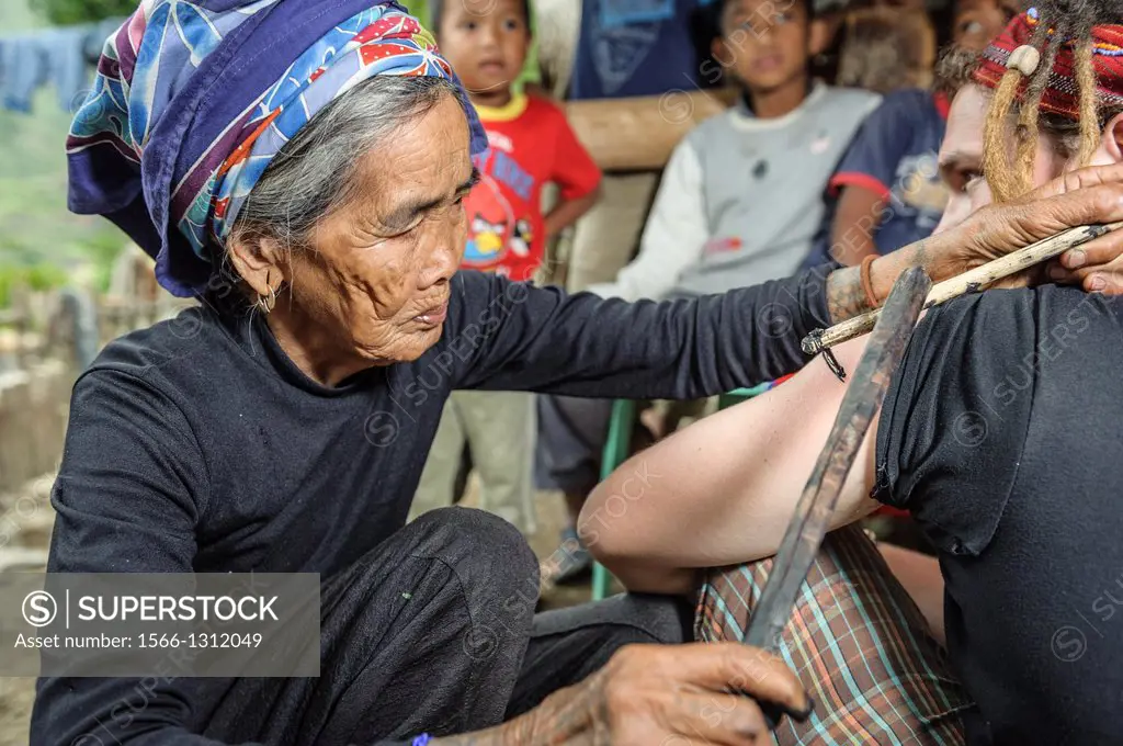 Woman tattooing a tourist in a traditional way, Kalinga, Philippines, Asia.