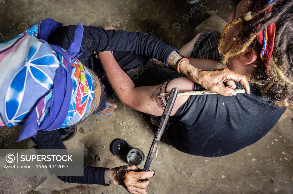 Woman tattooing a tourist in a traditional way, Kalinga, Philippines, Asia.