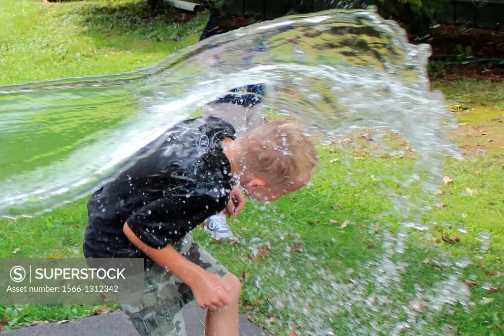 A young boy reacts as he´s doused by a pail of cold water as a parental prank.
