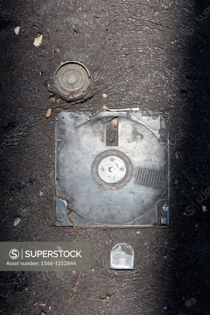 old floppy disk embedded in hot tarmac road surface in sun