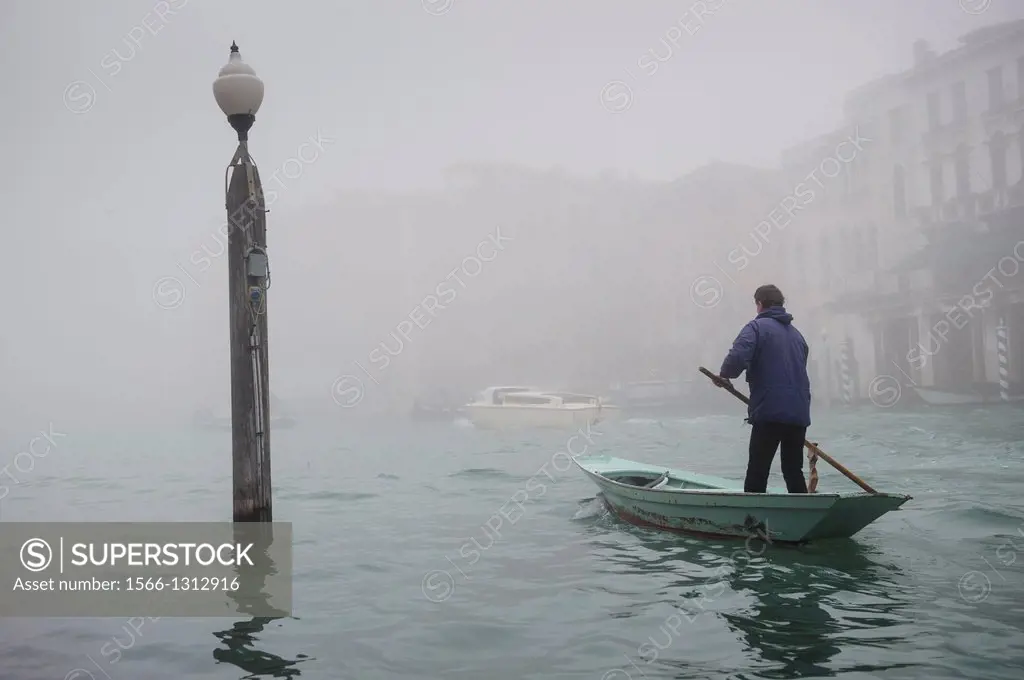 A man rowing along the Grand Canal in Venice Covered in thick fog, Italy.