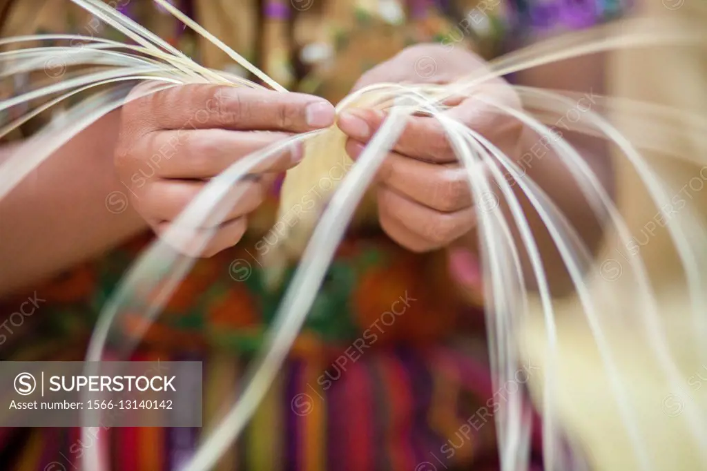Guatemala, Quetzaltenango, close up of weavers hands making straw mat