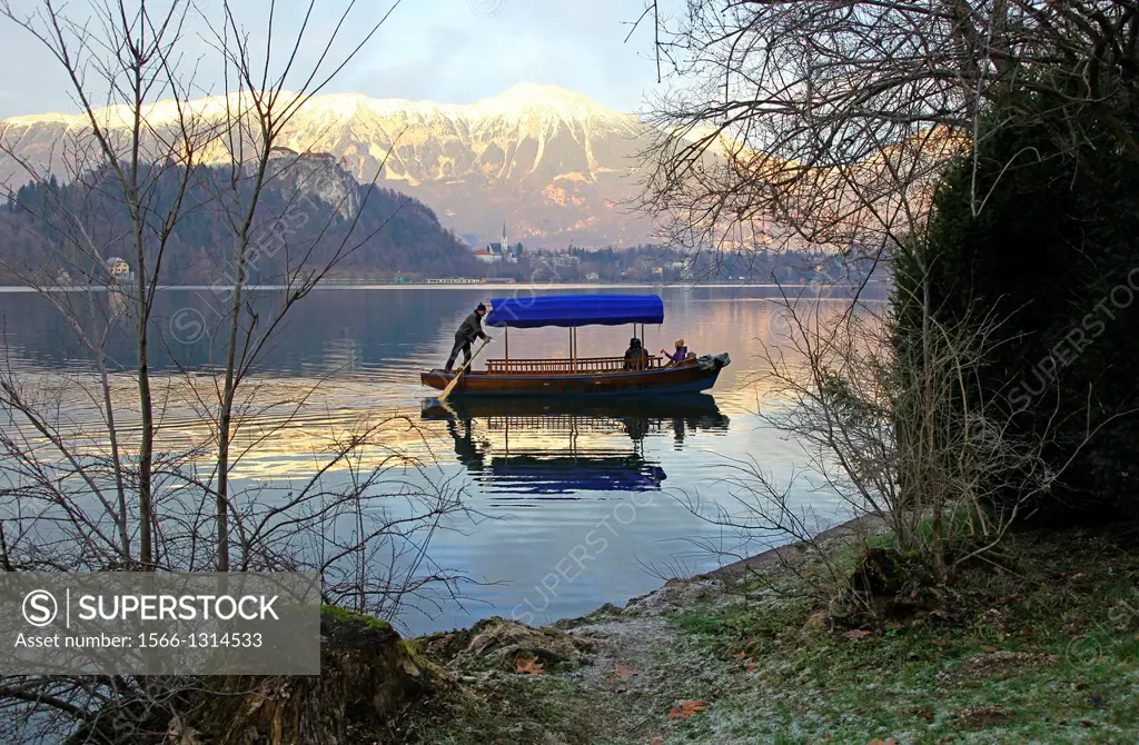 A man rowing a Pletna, a covered wooden rowing boat, on Lake Bled Slovenia.