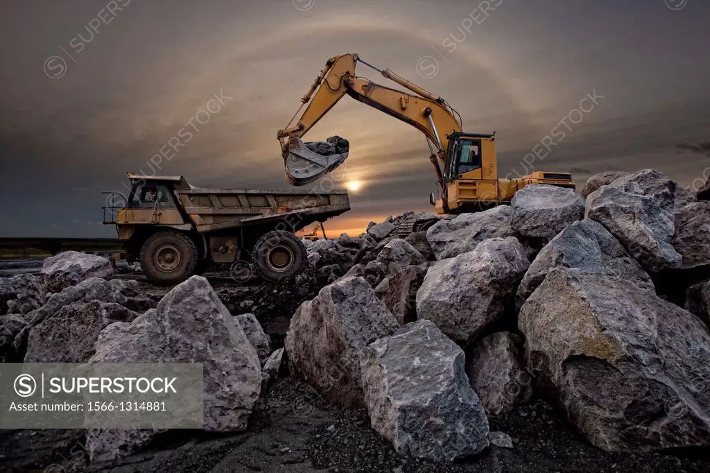 Filling dump truck with large boulders for harbor construction.