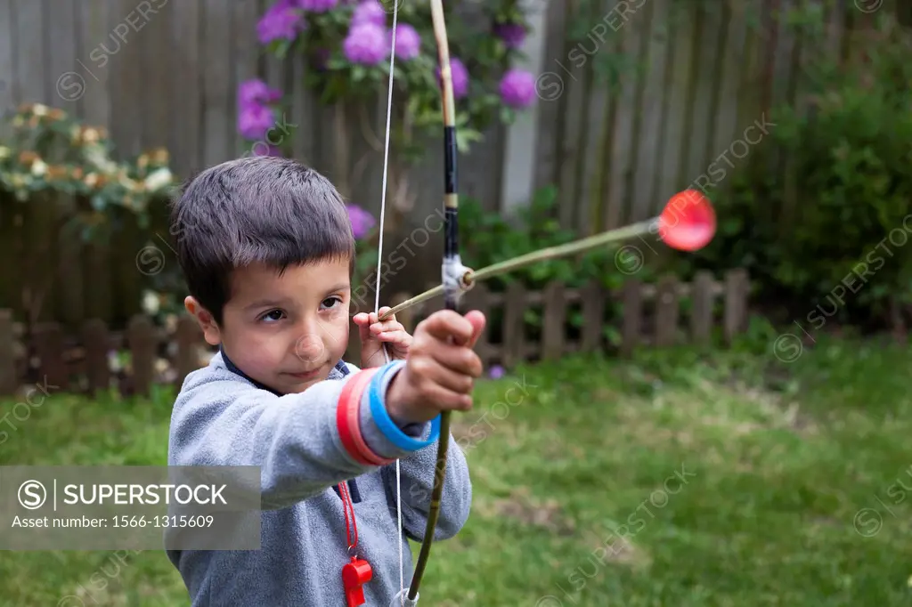 Boy aims with home-made bow and arrow.
