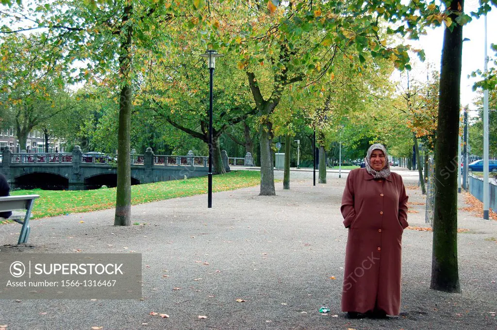 Rotterdam, Netherlands. Moslima woman, wearing a kerchief, wandering about a citypark.
