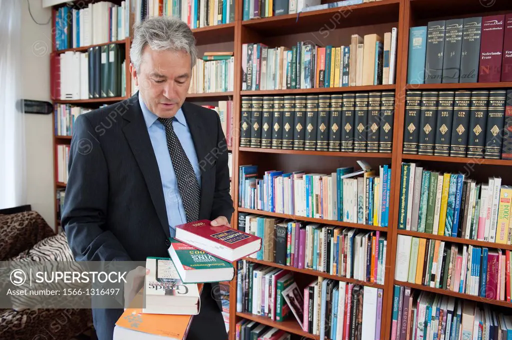 Breda, Netherlands. Wine broker reading books and references in his library at home.