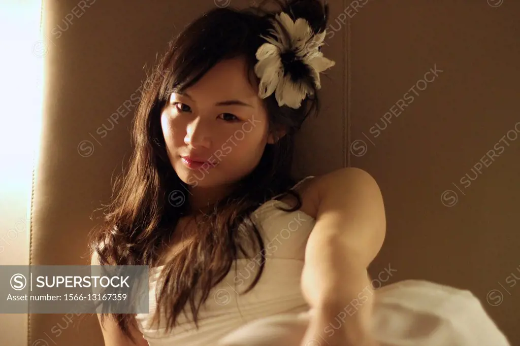 portrait of a beautiful young Chinese girl playing on bed.