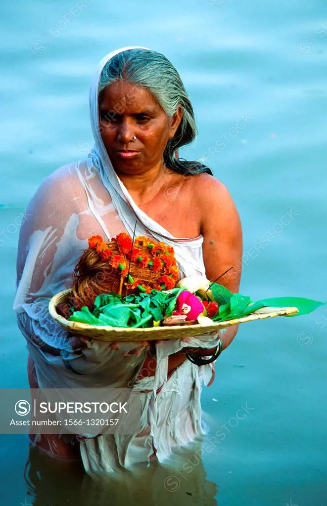 pregnant woman offers fruit to the Gods in the Ganges and prays for receiving a boy. Varanasi, India