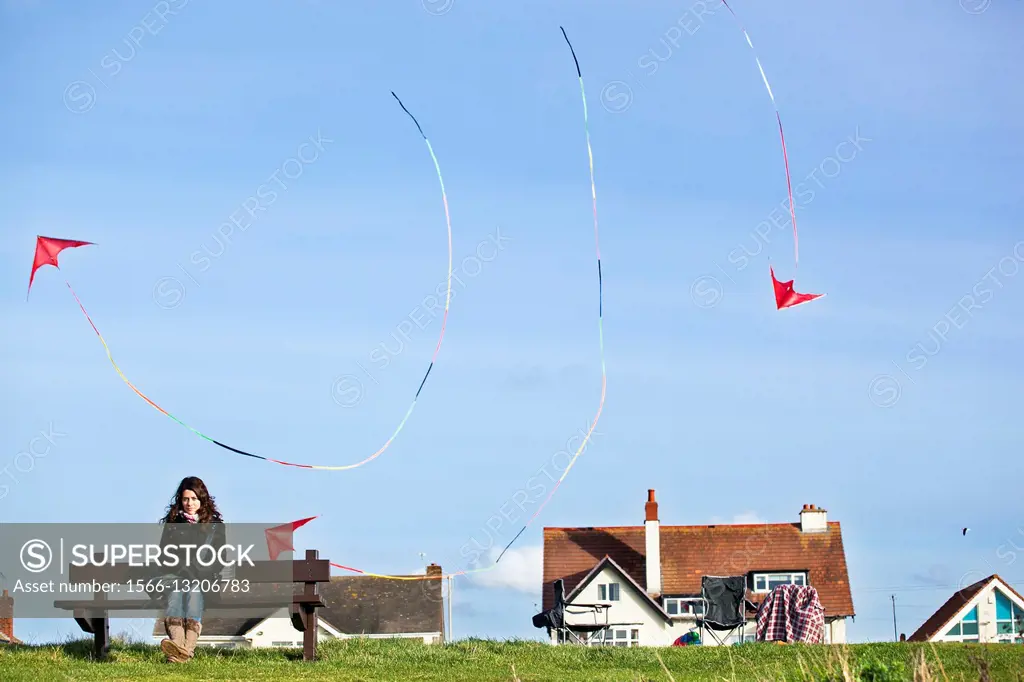 Woman on bench and kites flying