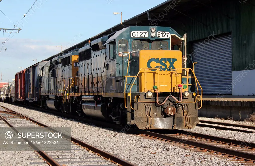 A CSX diesel engine pulling a string of freight cars past a warehouse in the city of New Orleans, Louisiana, USA.