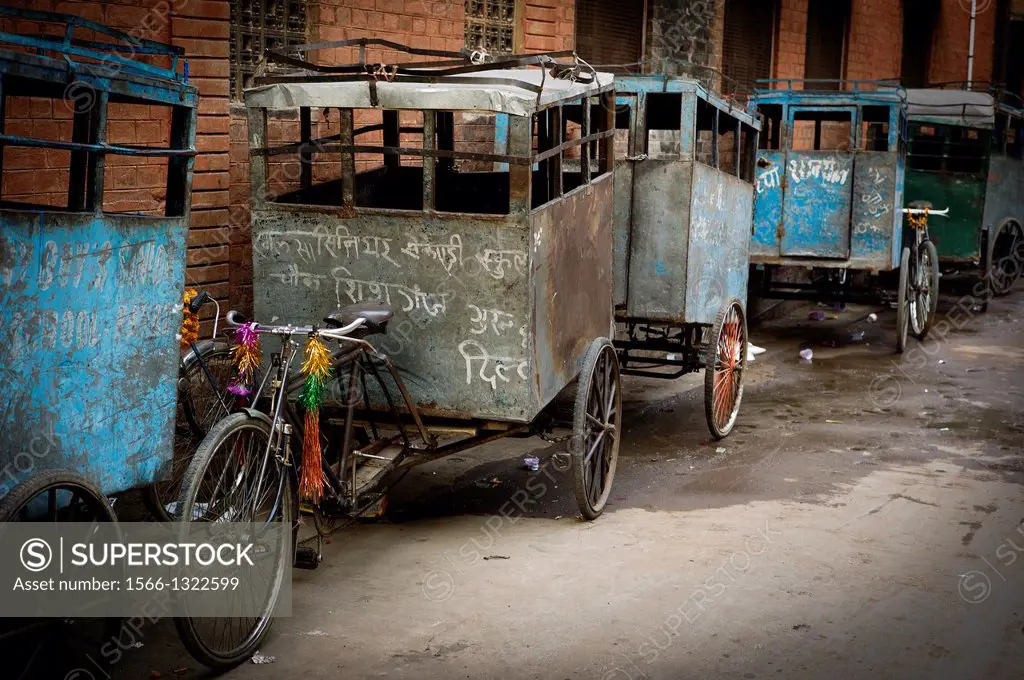 row of cycle rickshaw parked outside a school to transport children in the city of Delhi, India, Asia