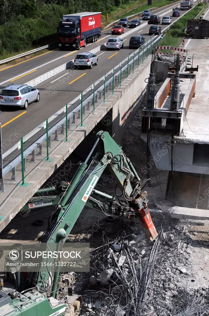 Green Liebherr hydraulic excavator during the demolition of a bridge