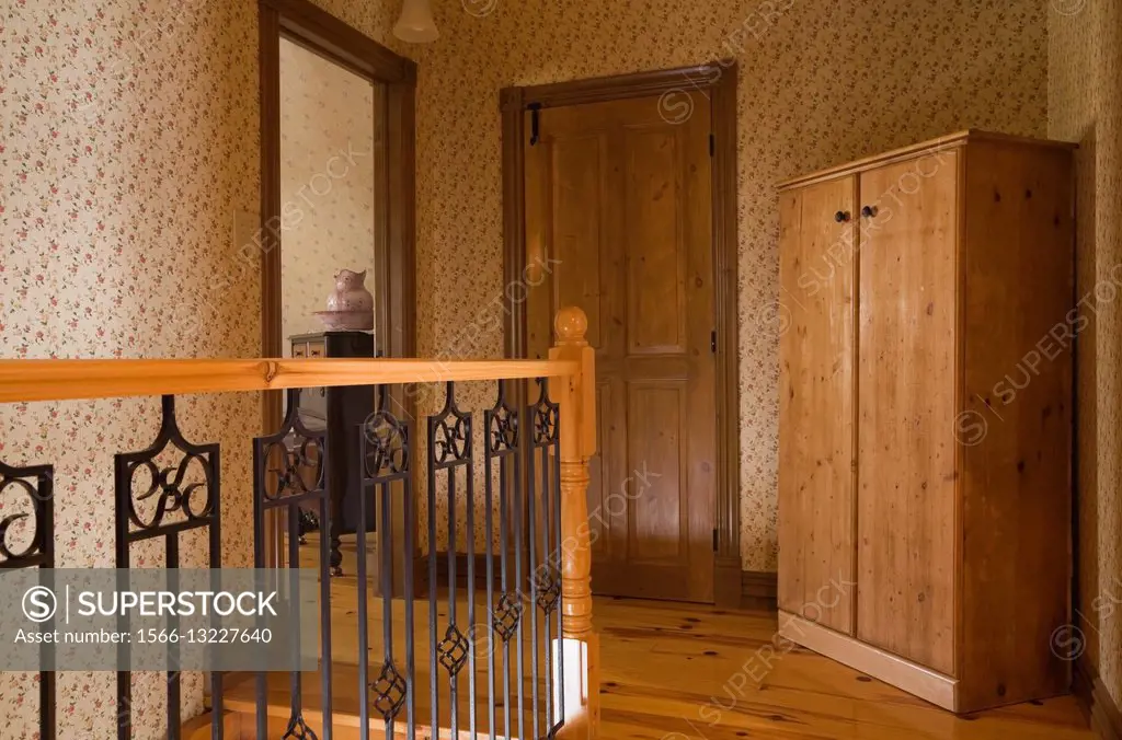 Railing and Armoire on the upstairs floor of a Canadiana cottage style fieldstone residential home built to look old in 2002, Quebec, Canada.