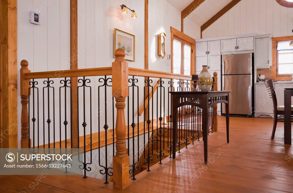 Railing surrounding the staircase inside the extension of a Canadiana cottage style fieldstone residential home built to look old in 2002, Quebec, Can...