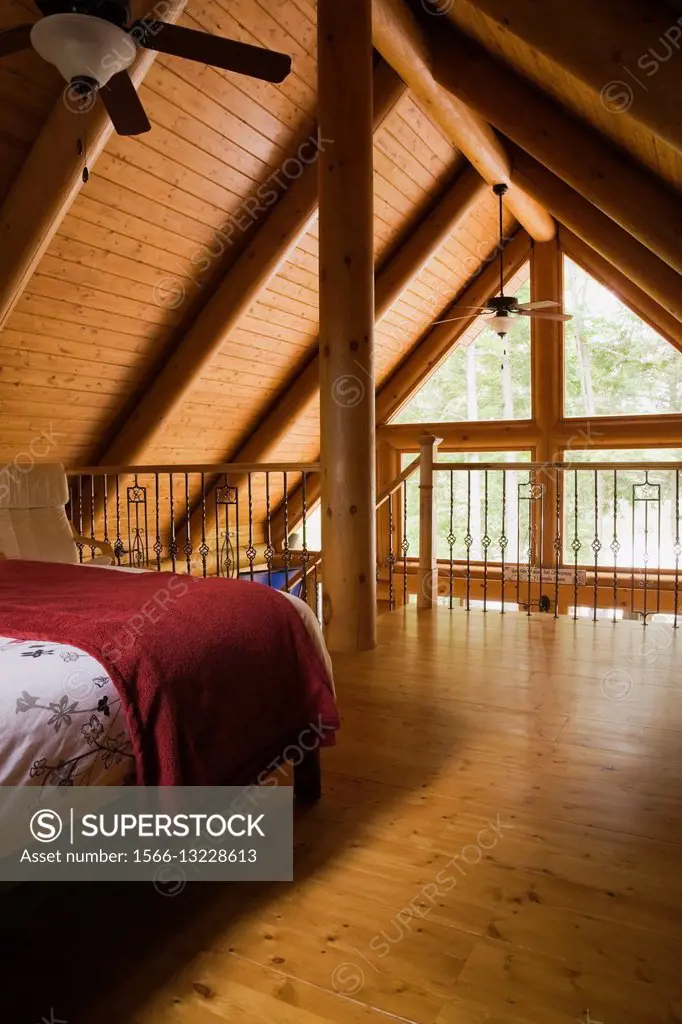 Partial view of the master bedroom on the upstairs floor inside a residential log home, Laurentians, Quebec, Canada