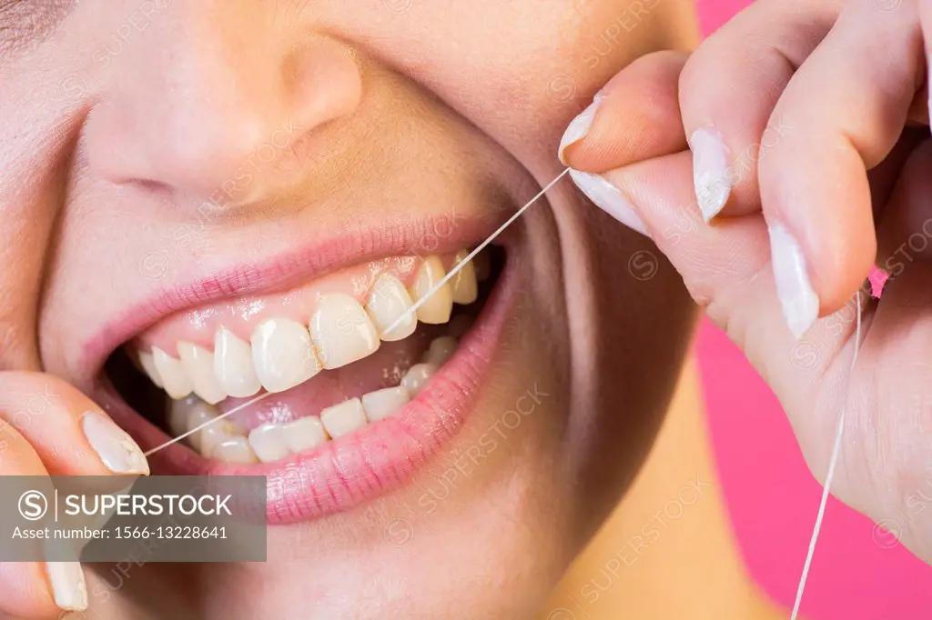 Close up of a woman flossing her teeth.