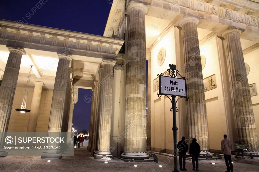 Berlin Brandenburg gate with christmas tree and snow at dusk.