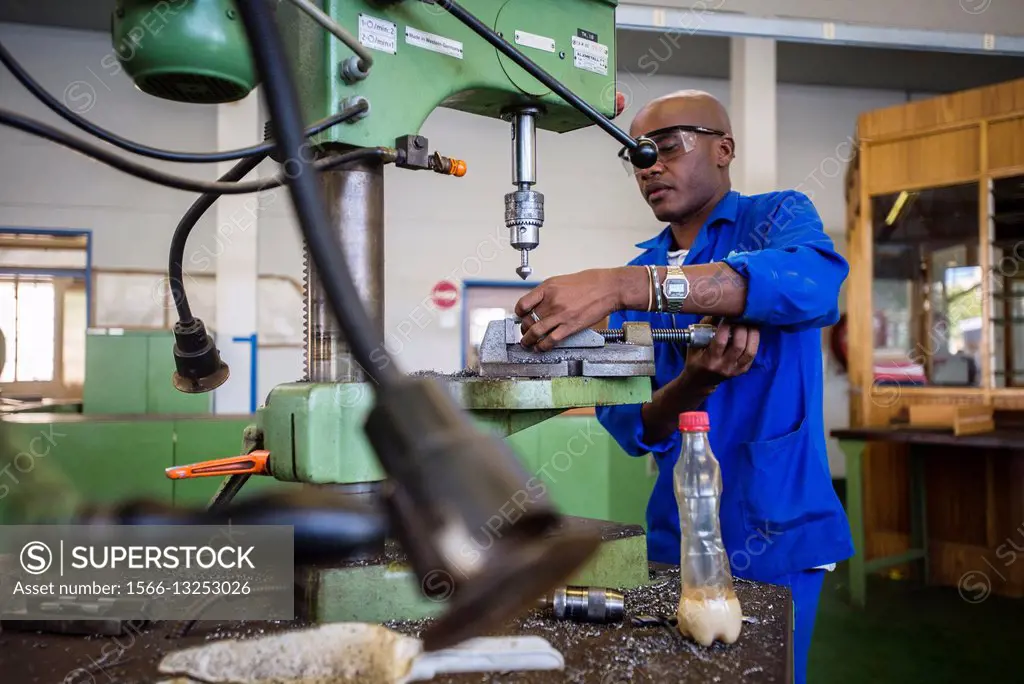 Fitting and Turning Trade of the Windhoek Vocational Training Centre, Namibia. Student works with a drill machine making holes through a piece of stee...