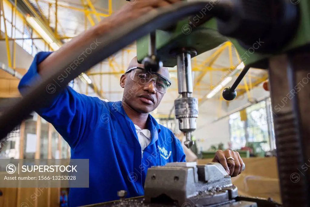 Fitting and Turning Trade of the Windhoek Vocational Training Centre, Namibia. Student works with a drill machine making holes through a piece of stee...