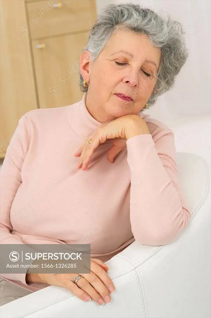 Senior woman in pink resting head under chin asleep