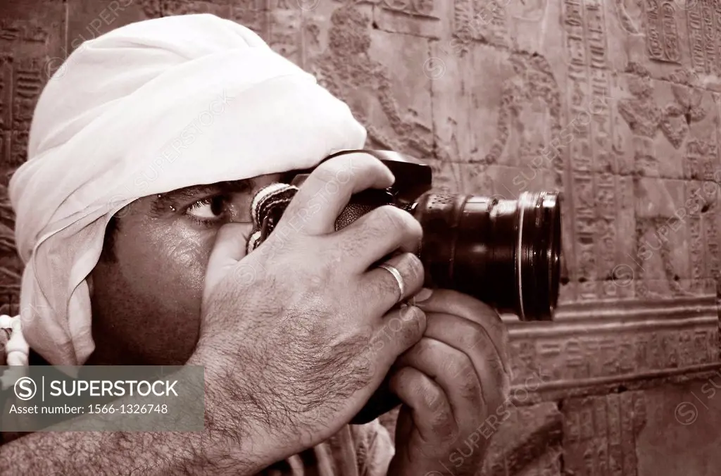 Press photojournalist is holding a camera with a zoom lens and photographing archaeology.