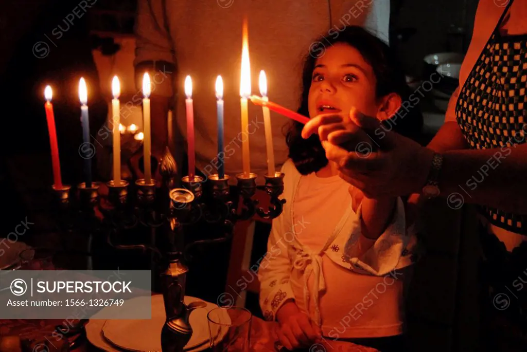 A family is lighting a candle for the Jewish holiday of Hanukkah.