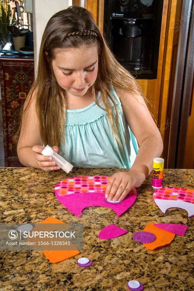 Using a glue stick, an eight-year-old girl assembles cutouts for a craft project at home in Laguna Beach, CA.