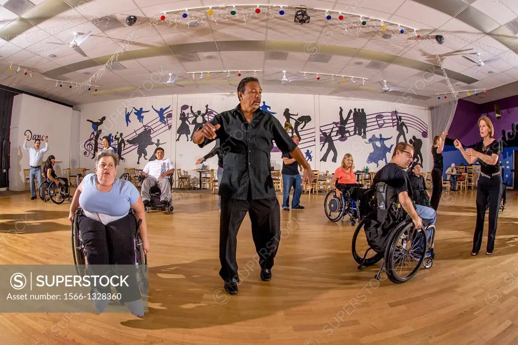 An African American dance teacher instructs handicapped adults perform a wheelchair dance with normal adults in San Diego, CA. The physical benefits o...