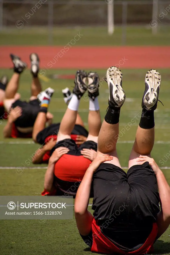 Multiethnic high school athletes limber up with flexibility exercises as they begin spring football practice in San Clemente, CA.High school athletes ...