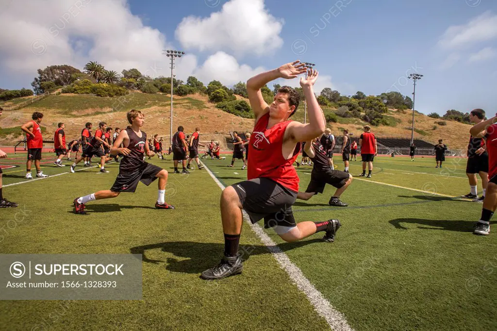 High school athletes limber up with flexibility exercises as they begin spring football practice in San Clemente, CA.