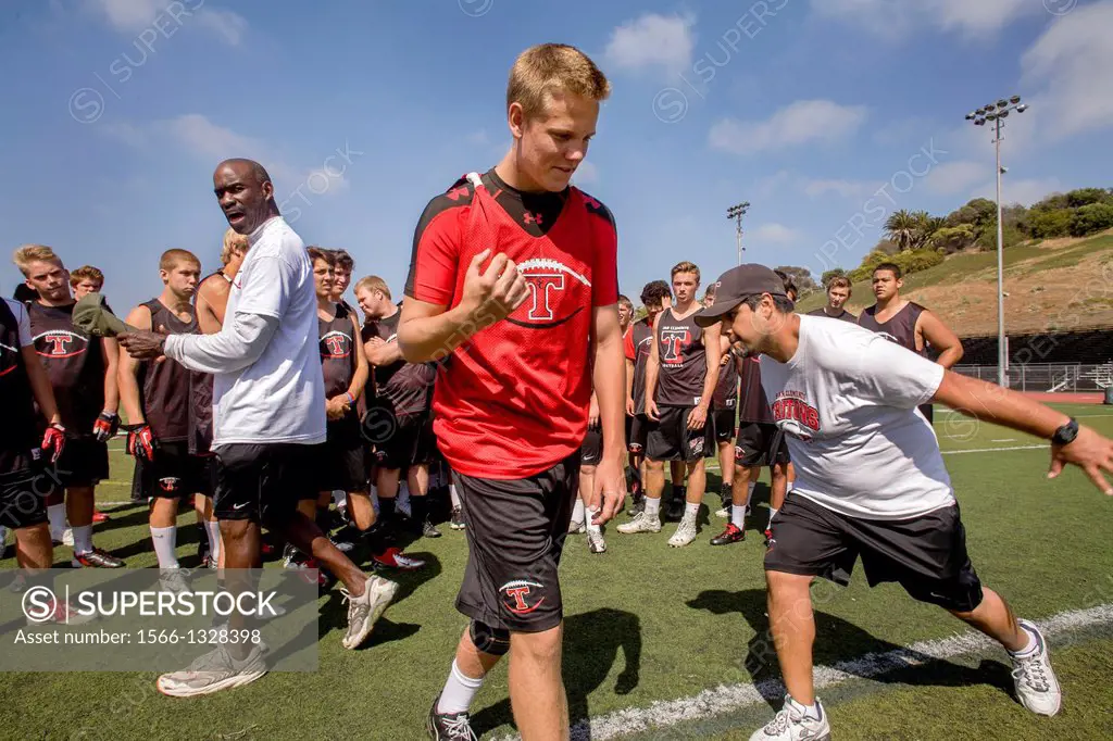 A proud high school athlete is awarded a position on the team during spring football practice in San Clemente, CA. Note coaches.