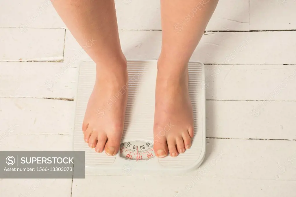 Barefooted woman standing on the scale measure her bodyweight.