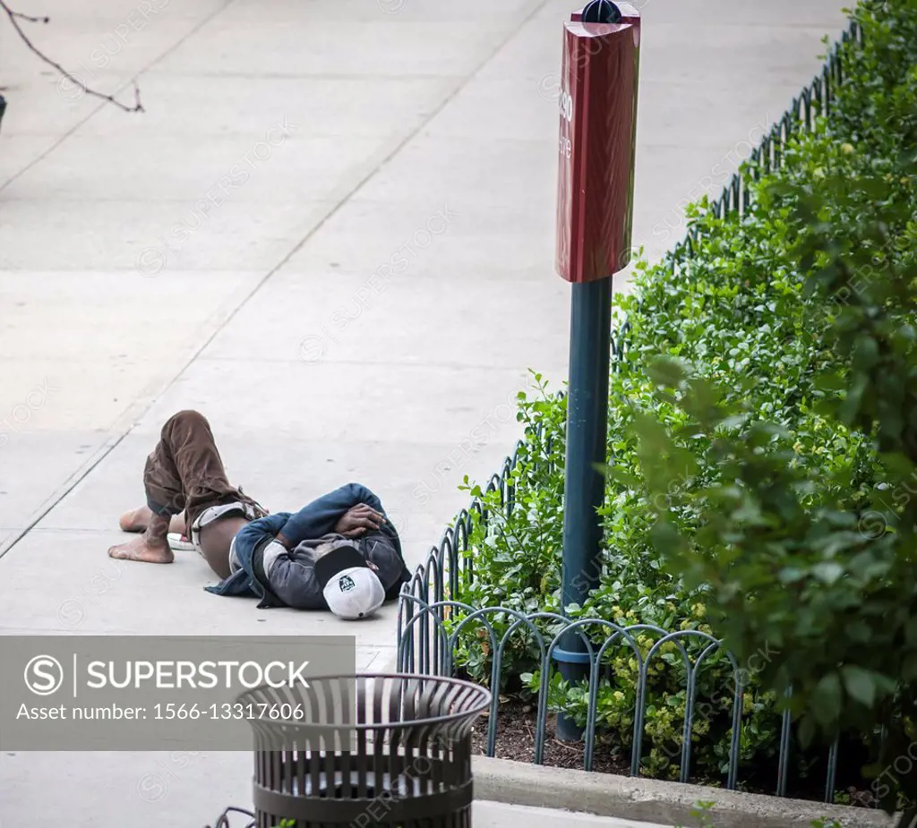 A homeless individual sleeps on the sidewalk in the Chelsea neighborhood of New York