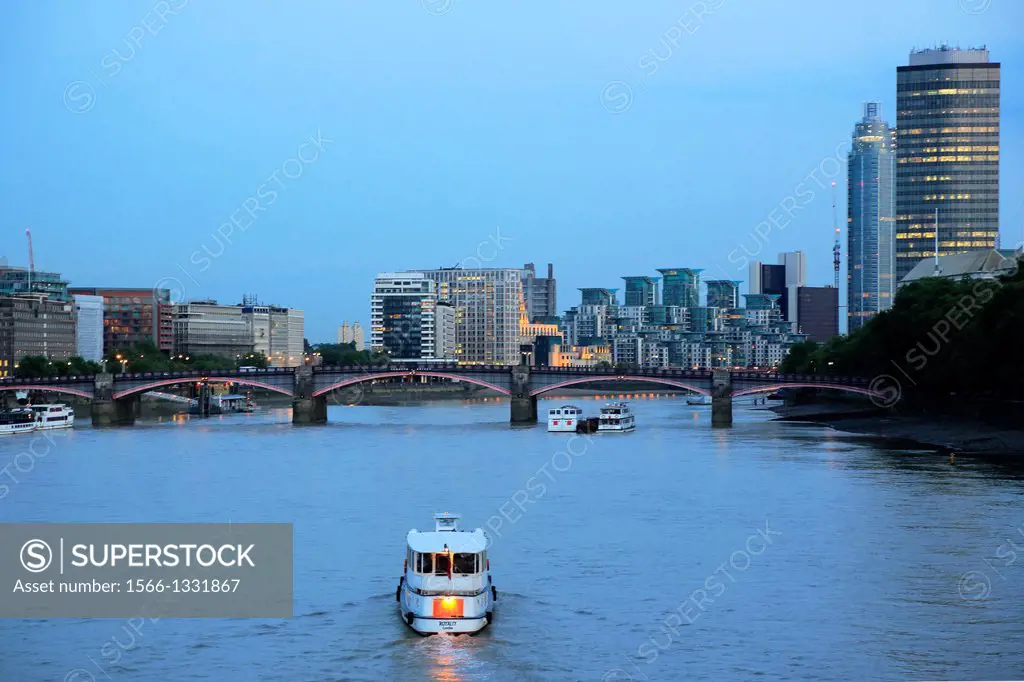 Boat in River Thames with Lambeth Bridge and office towers and apartment buildings in the background, London, England, UK