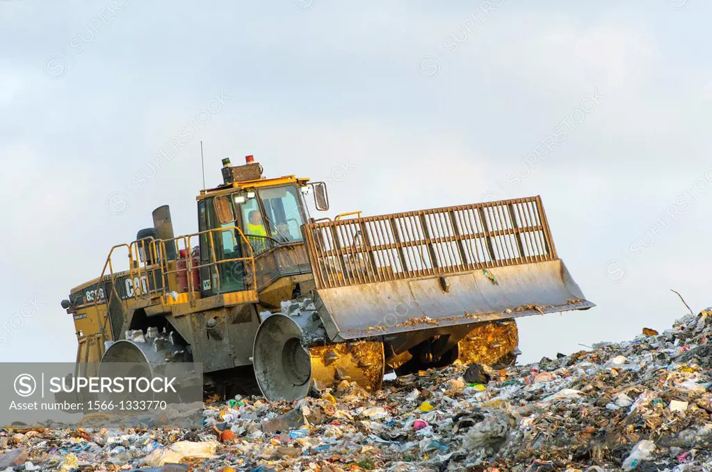 Heavy equipment pushing garbage at a sanitary landfill. After loads are deposited, compactors or dozers are used to spread and compact the waste on th...
