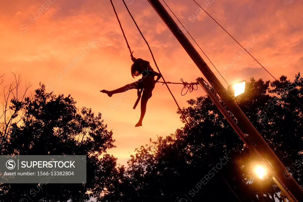 A young girl on rope swing at sunset  