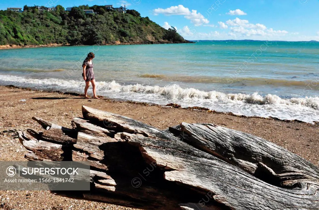 A woman walks on a beach in Waiheke Island, New Zealand.