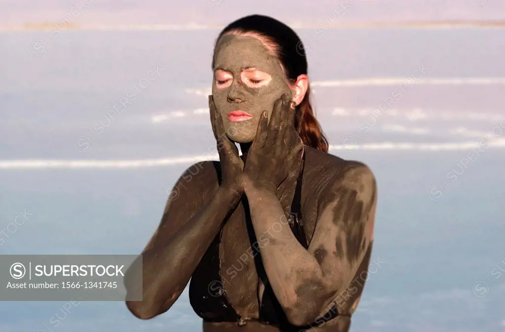 A young woman in a bathing suit is enjoying the natural mineral mud sourced from the dead Sea, Israel.