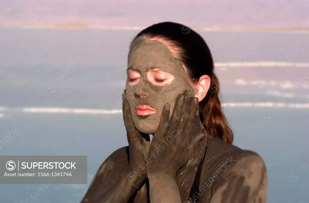 A young woman in a bathing suit is enjoying the natural mineral mud sourced from the dead Sea, Israel.