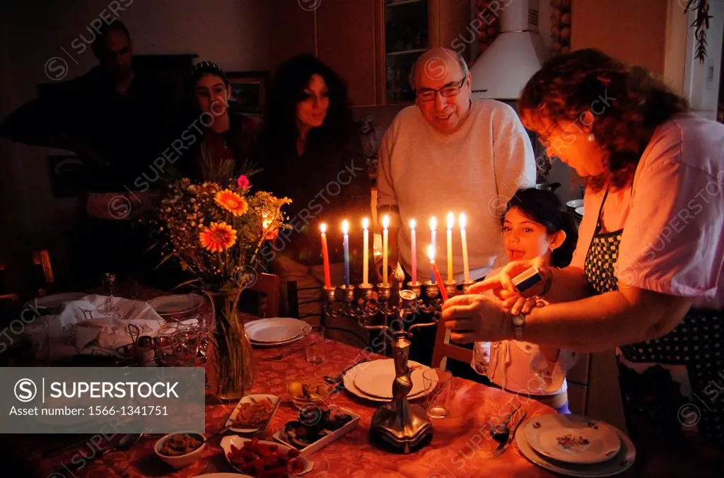 A family is lighting a candle for the Jewish holiday of Hanukkah. Hanukkah or Chanukah, Chanukkah, or Chanuka, also known as the Festival of Lights, i...
