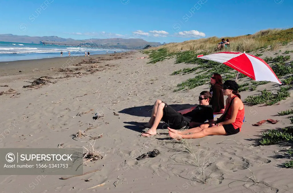 People enjoy the sea and sand at a beach in Christchurch, New Zealand.