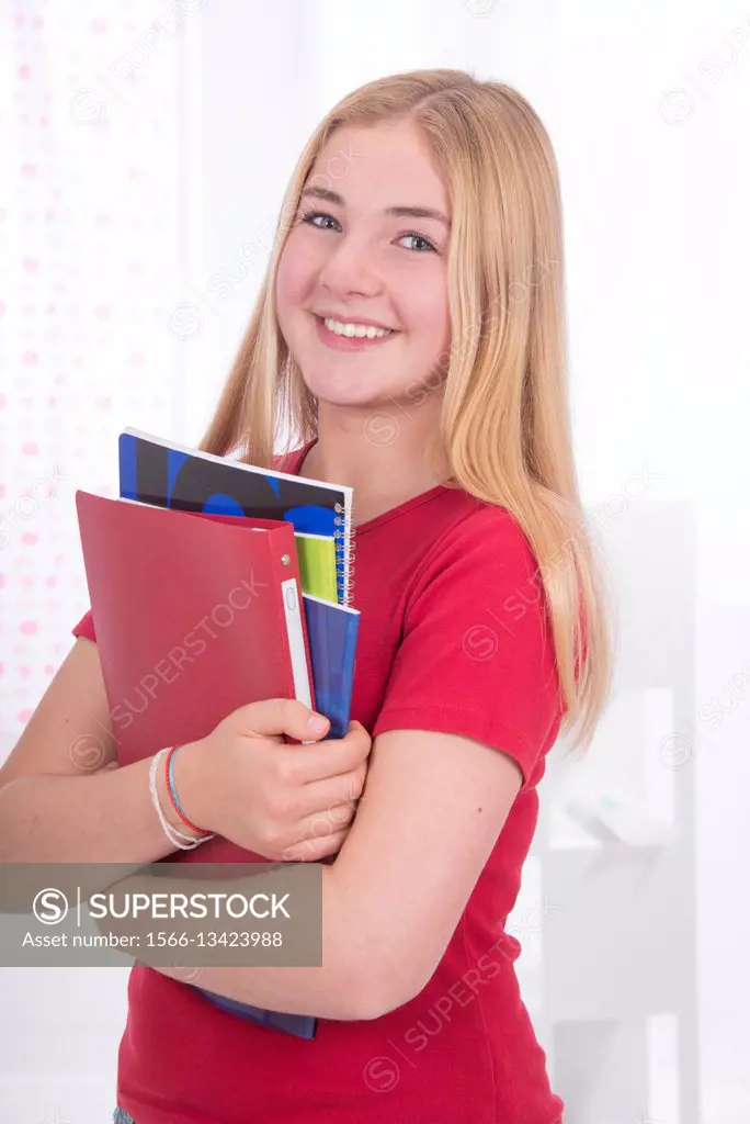 young school girl, 15 year old, in red, with a broad smile, holding her copybooks in her arms